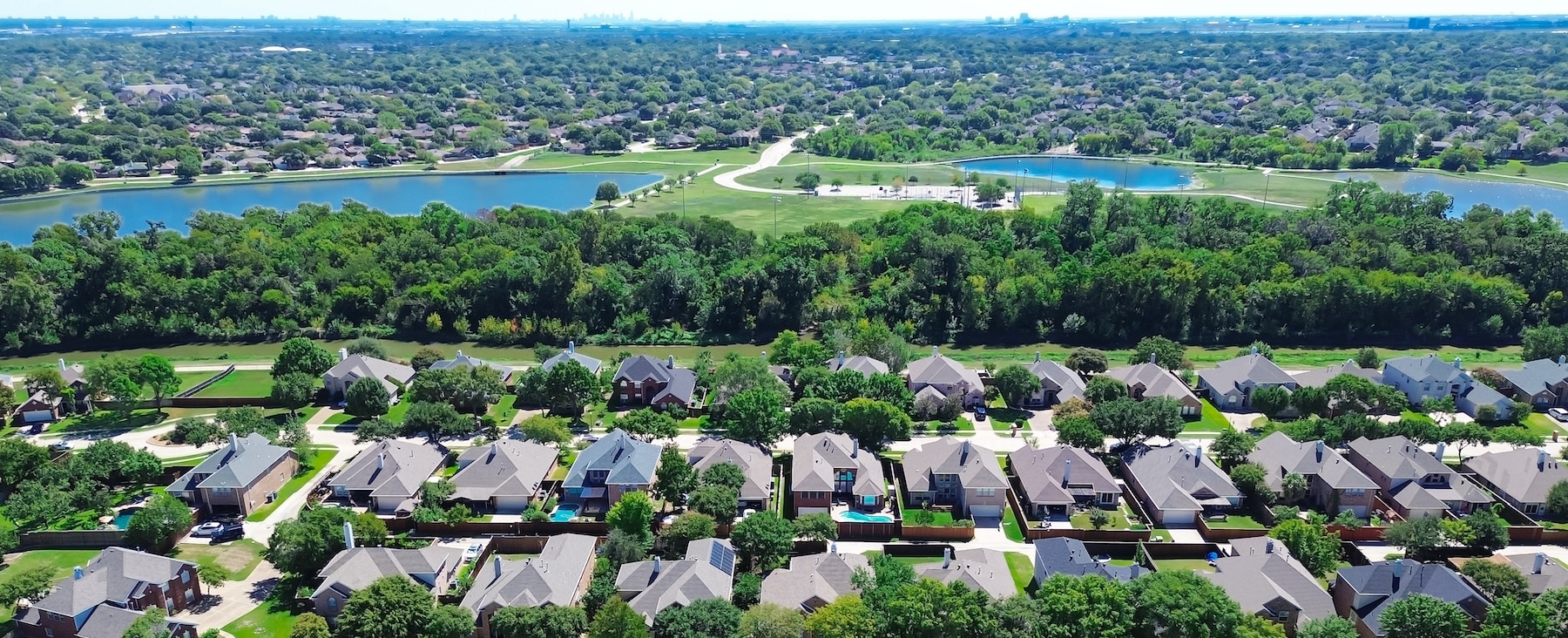 Panorama aerial upscale houses with swimming pool, solar roofing near suburban park creek, lake, pond, lush green urban forest suburb Dallas Fort Worth Metroplex, neighborhood hood Coppell Texas